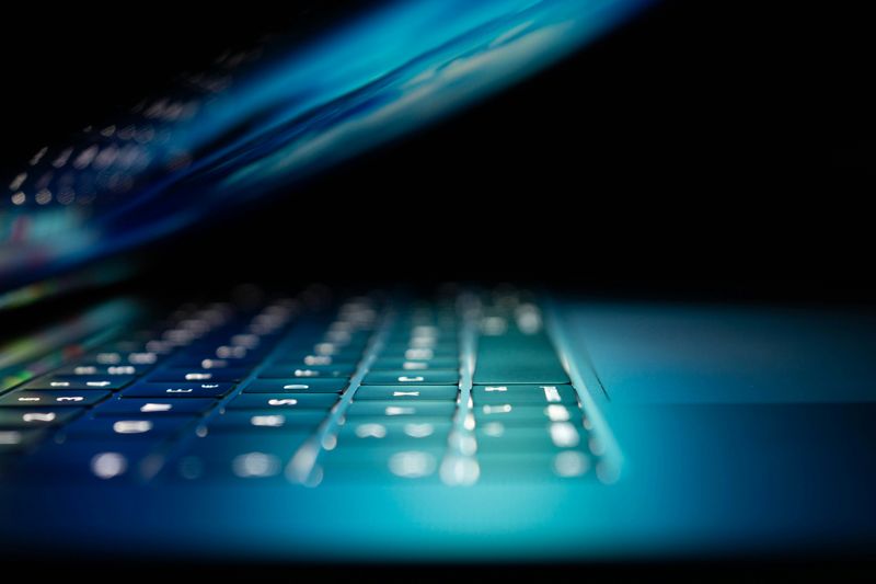 Close-up of a laptop keyboard lit by a blue screen glow